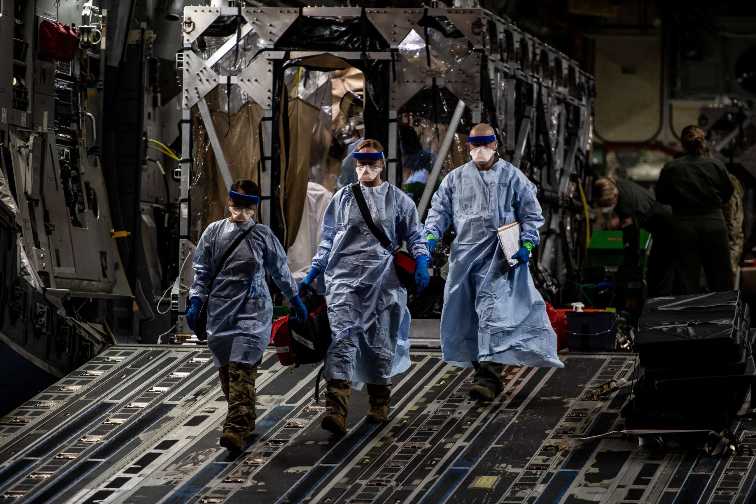 PHOTO: Three U.S. Air Force medical Airmen exit a C-17 Globemaster III aircraft following the first-ever operational use of the Transport Isolation System at Ramstein Air Base, Germany, April 10, 2020.