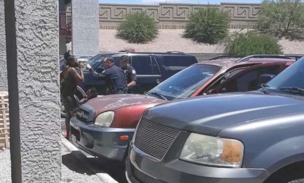 PHOTO: A video on a cell phone shows policemen from the Phoenix Police Department after sweeping Dravon Ames, handcuffed, and pointing a rifle at a pregnant mother with her two young daughters on May 27, 2019.