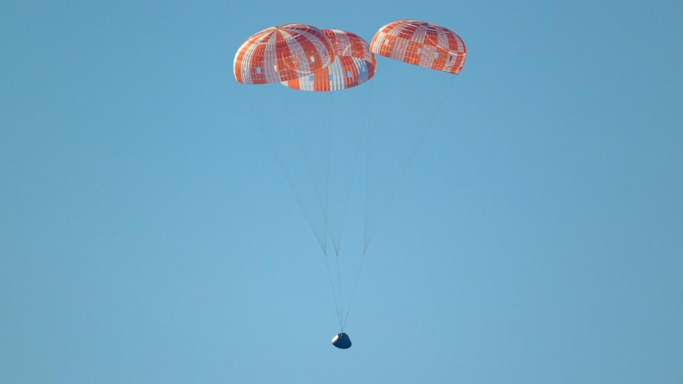 PHOTO: NASA's Orion spacecraft with Artemis II crewmembers, Reid Wiseman, Victor Glover, Christina Koch and Jeremy Hansen is seen under parachutes as it splashes down in the Pacific Ocean off the coast of San Diego, April 10, 2026. 