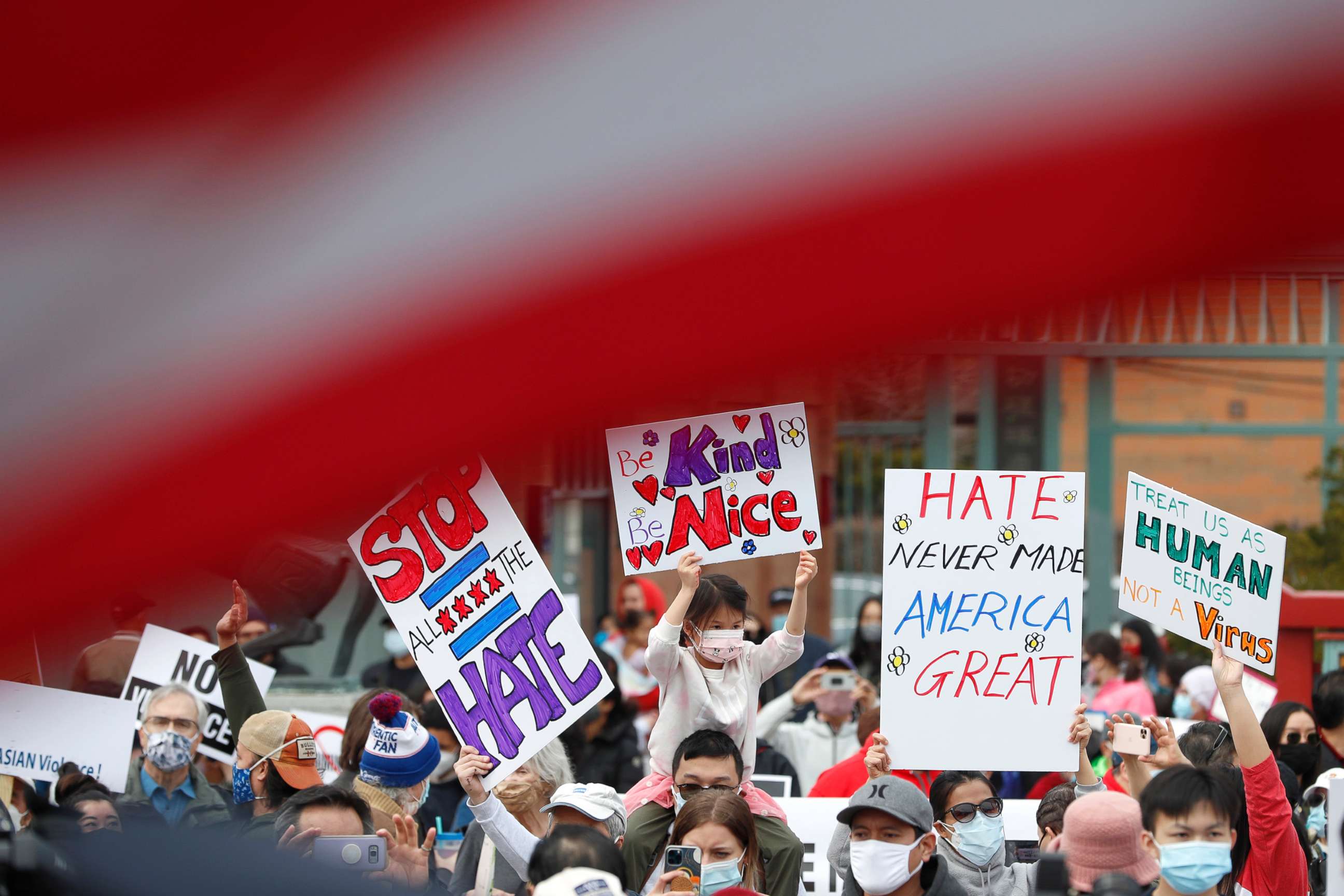 PHOTO: Demonstrators holding signs are seen underneath an American Flag as they take part in a rally against Asian hate crimes, March 27, 2021 at Chinatown in Chicago.