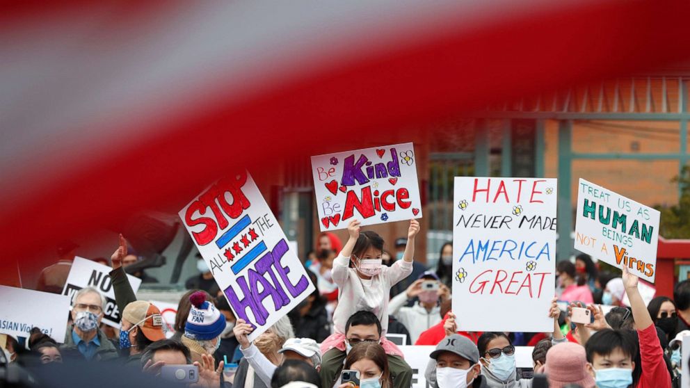 PHOTO: Demonstrators holding signs are seen underneath an American Flag as they take part in a rally against Asian hate crimes, March 27, 2021 at Chinatown in Chicago.