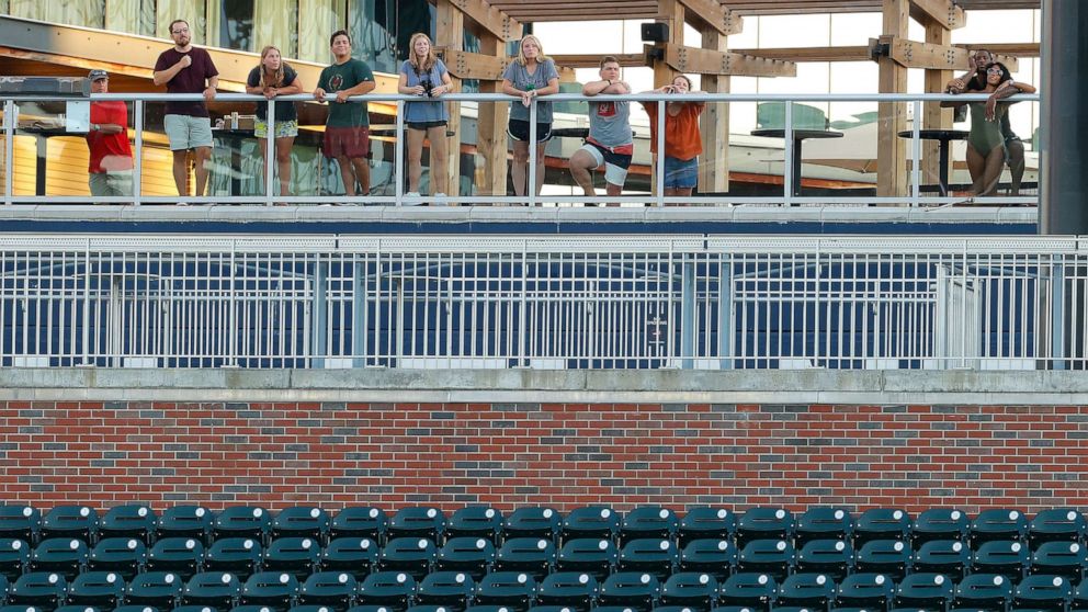 PHOTO: Guests of the Omni Hotel look on from the swimming pool area as they watch Atlanta Braves in their first intrasquad game of summer workouts at Truist Park, on July 13, 2020, in Atlanta.