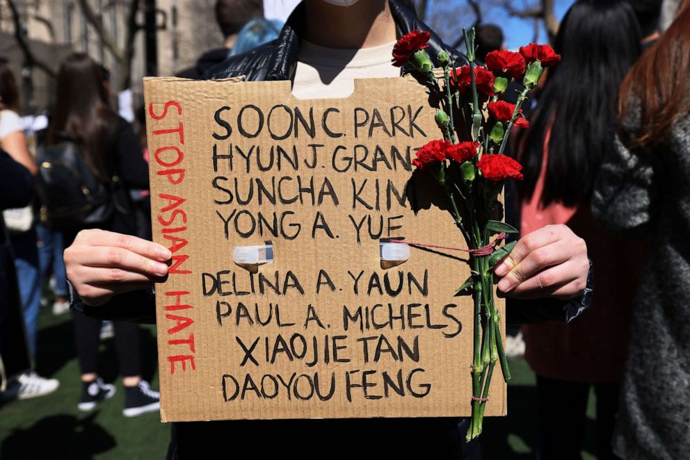 PHOTO: Amy Zhao holds up a sign and flowers at a rally against hate, March 21, 2021, in the Chinatown neighborhood of New York.