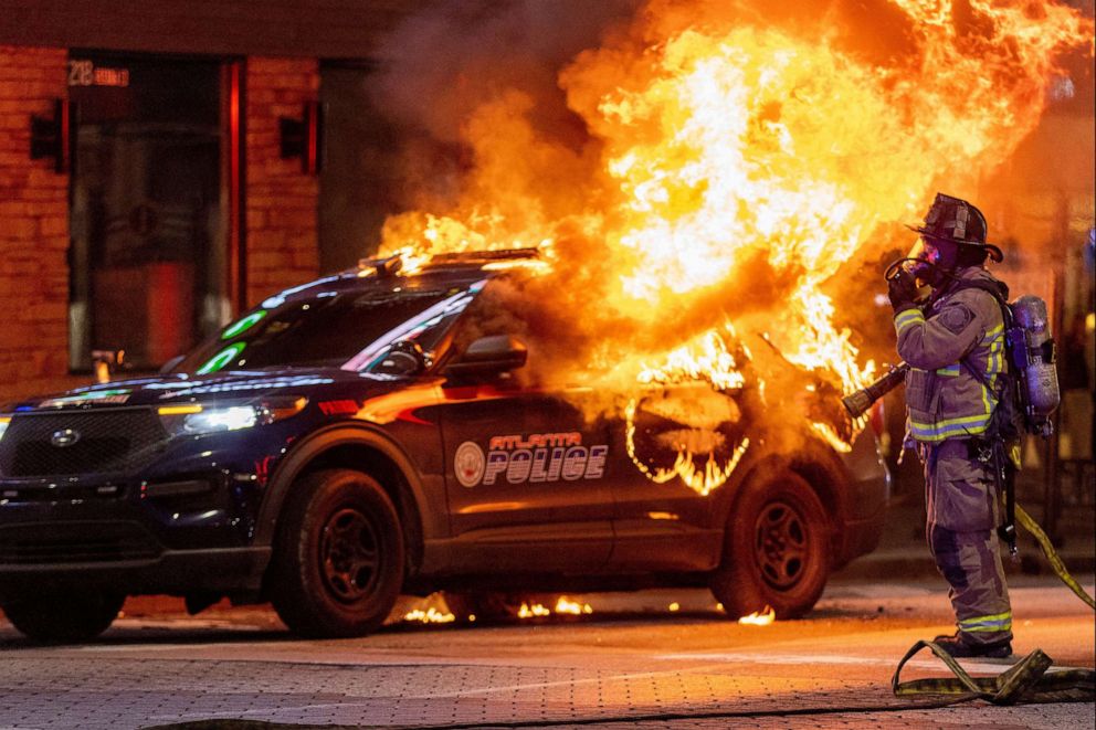 PHOTO: Atlanta firefighters prepared to extinguish a police car that was set afire during a Forest Defenders protest in Atlanta, on Jan 21, 2023.