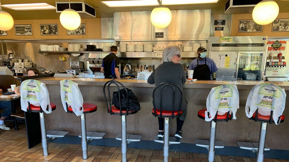 PHOTO: Kim Kaseta sits at the counter of a Waffle House for breakfast in Atlanta, as Georgia relaxed its Coronavirus pandemic restrictions to allow restaurants to provide limited dine-in service, April 27, 2020.