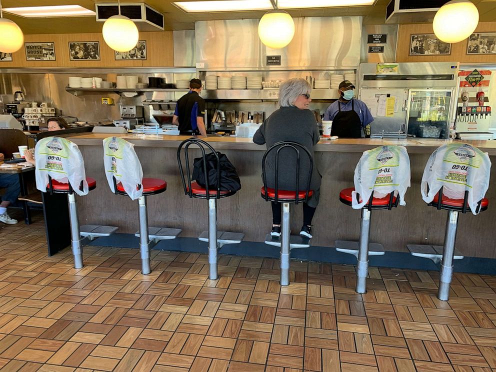 PHOTO: Kim Kaseta sits at the counter of a Waffle House for breakfast in Atlanta, as Georgia relaxed its Coronavirus pandemic restrictions to allow restaurants to provide limited dine-in service, April 27, 2020.