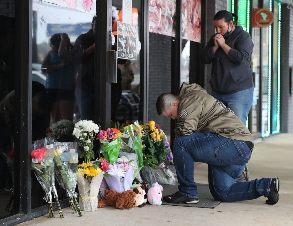 PHOTO: Army veteran Latrelle Rolling, left, and Jessica Lang, right, pause to pray after dropping off flowers at Young's Asian Massage on March 17, 2021, in Acworth, Ga.