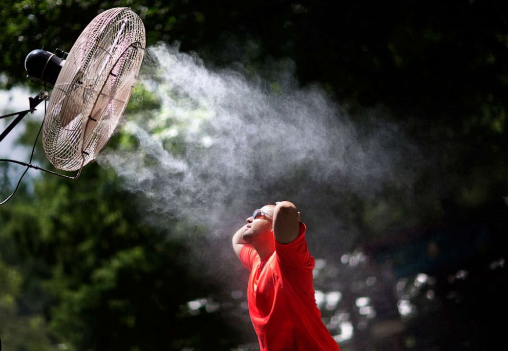 PHOTO: A visitor cools off under a misting fan while visiting Zoo Atlanta, July 15, 2015, in Atlanta.
