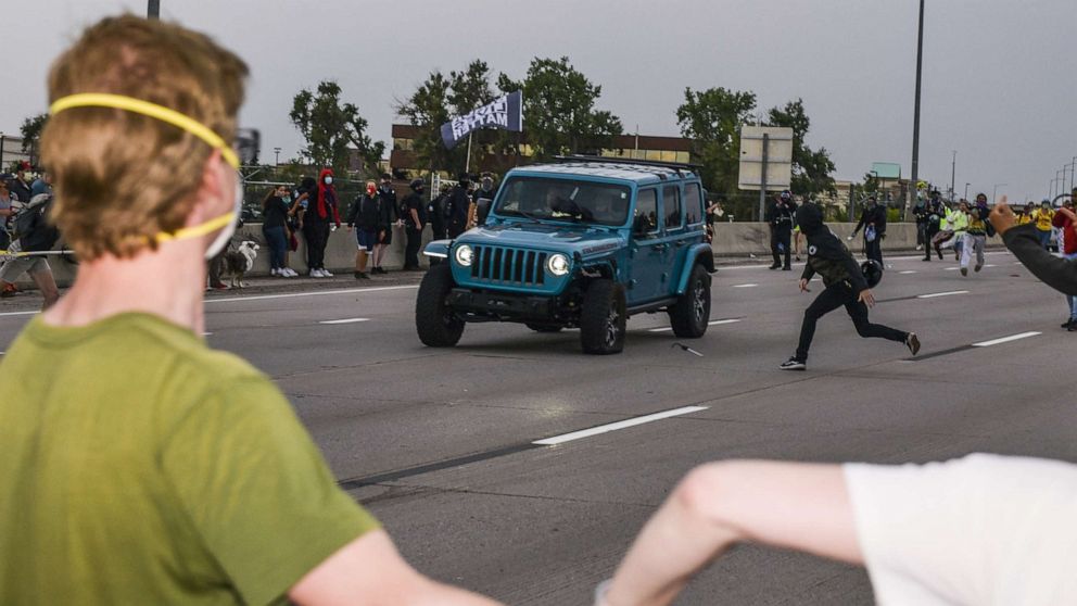 PHOTO: People run to get out of the way as a Jeep speeds through a crowd of people protesting the death of Elijah McClain on I-225 on July 25, 2020 in Aurora, Colorado.