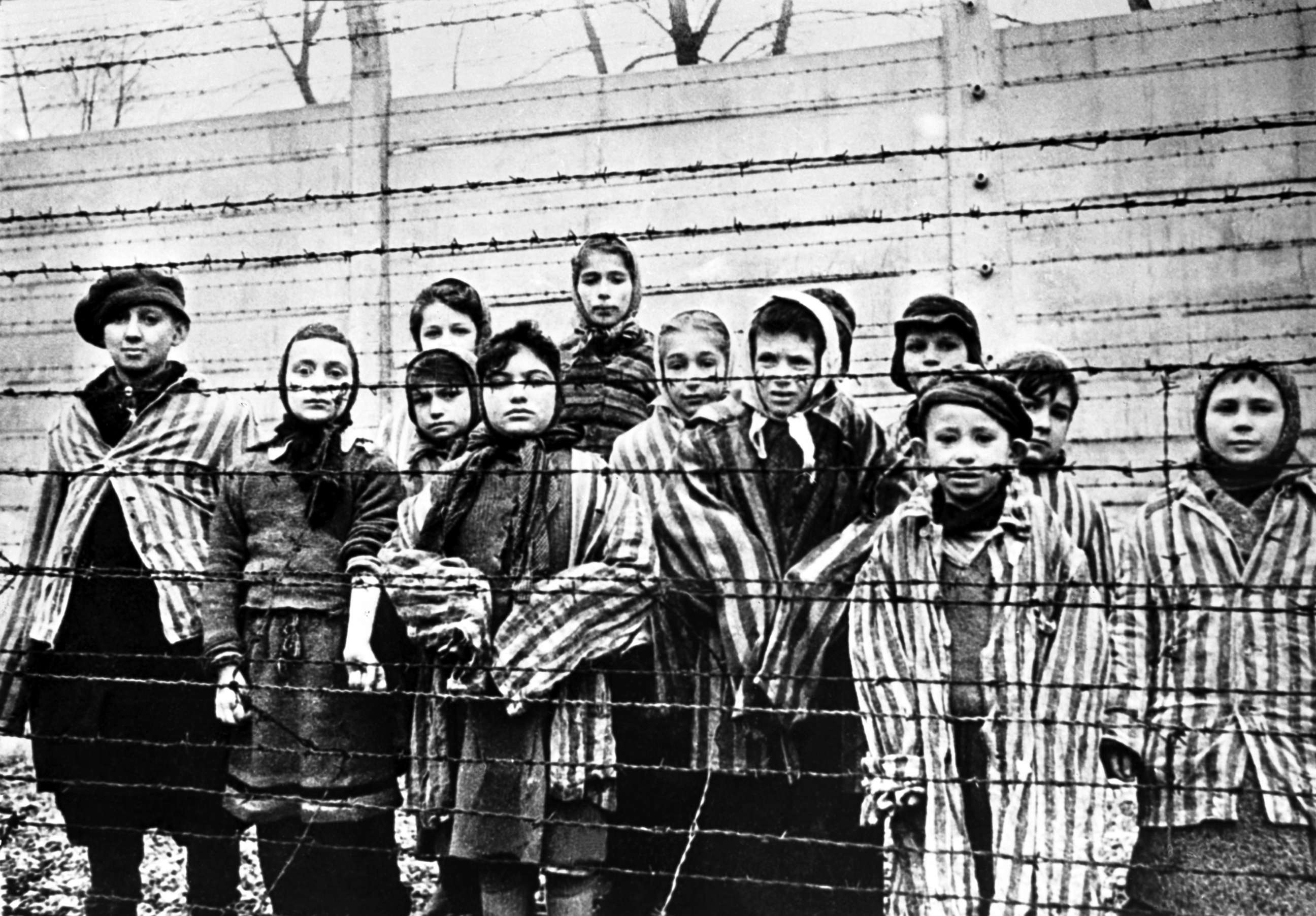 PHOTO: A group of child survivors stand behind a barbed wire fence at the Nazi concentration camp at Auschwitz-Birkenau in southern Poland, on the day of the camp's liberation by the Soviet Army, Jan. 27, 1945.