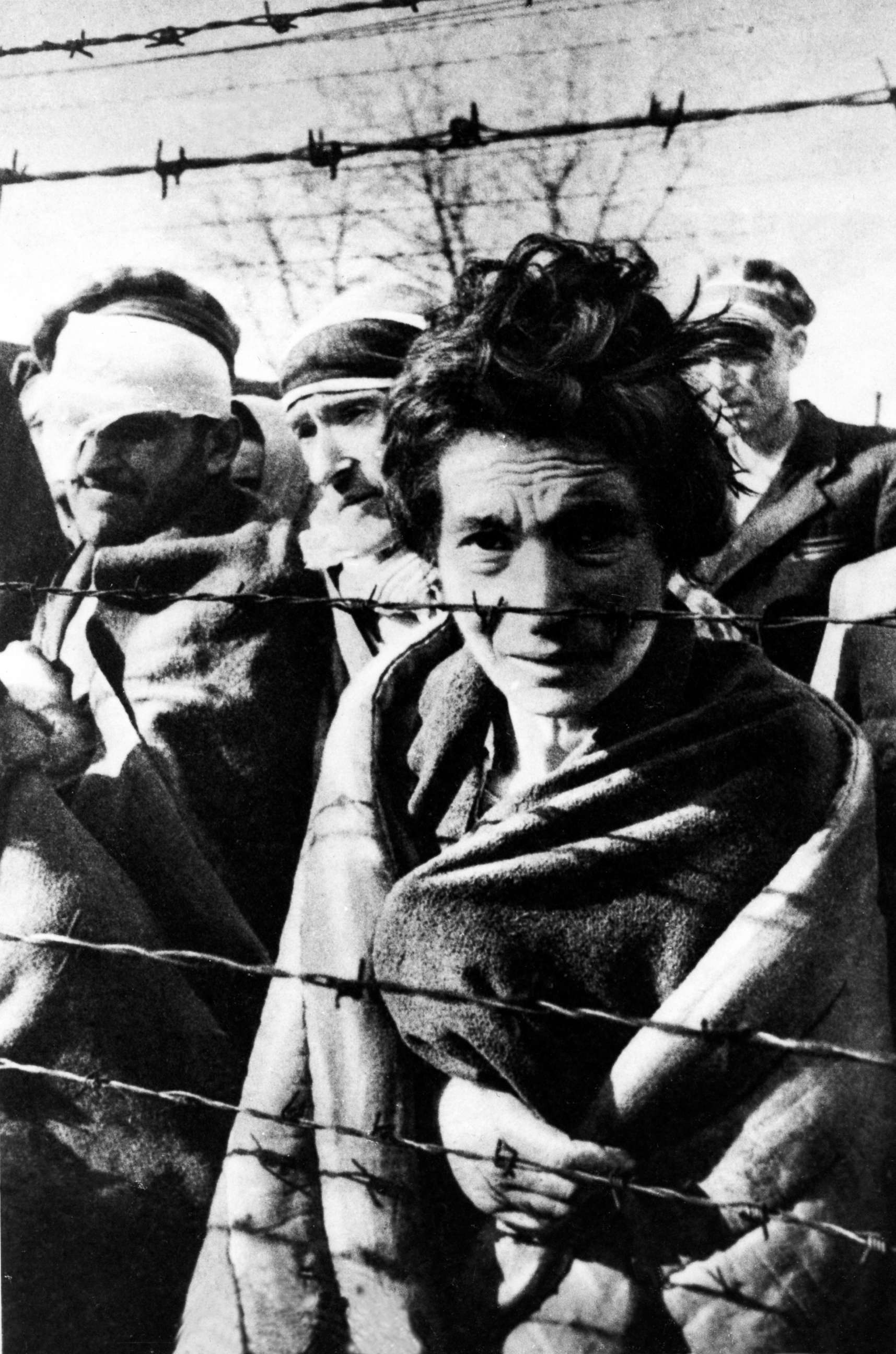 PHOTO: A few of the survivors of Auschwitz stand near a fence during the arrival of the Soviet Army on Jan. 27, 1945.