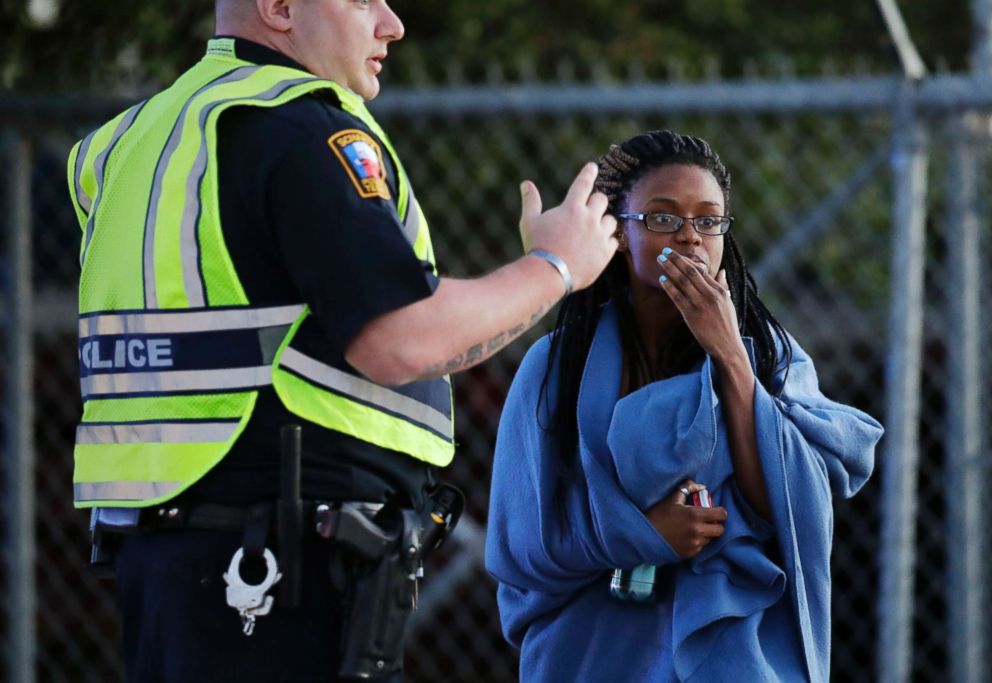 PHOTO: An employee wrapped in a blanket talks to a police officer after she was evacuated at a FedEx distribution center where a package exploded, March 20, 2018, in Schertz, Texas.