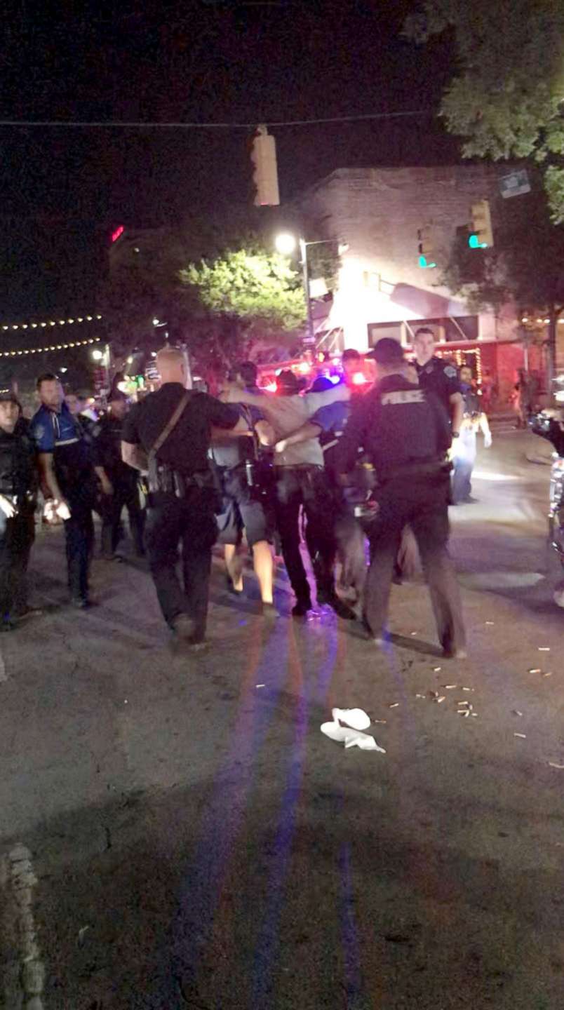 PHOTO: Police officers escort a victim (C) after gunfire erupted at a busy entertainment district in Austin, Texas, June 12, 2021, in this still image taken from video provided on social media.