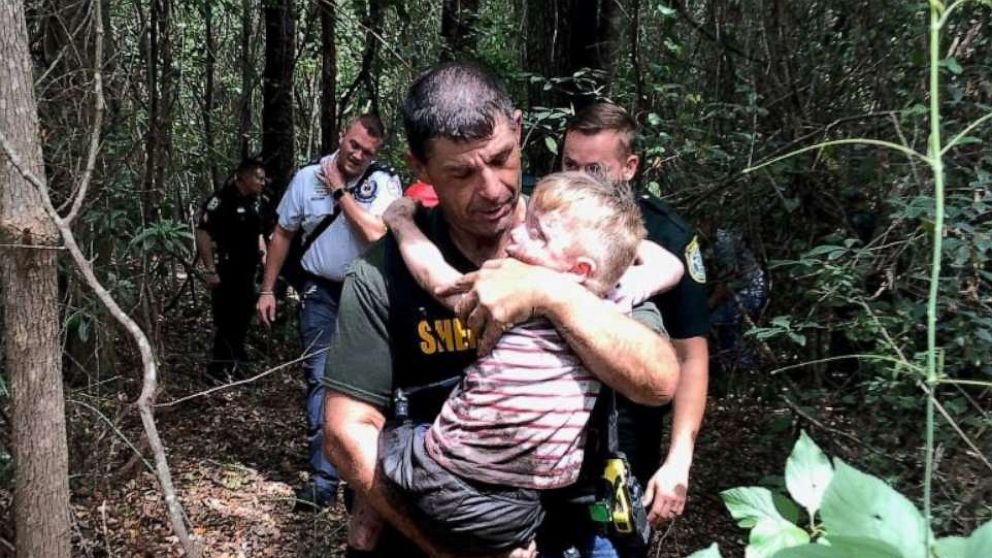 PHOTO: Boy being carried out of forest by his rescuers.