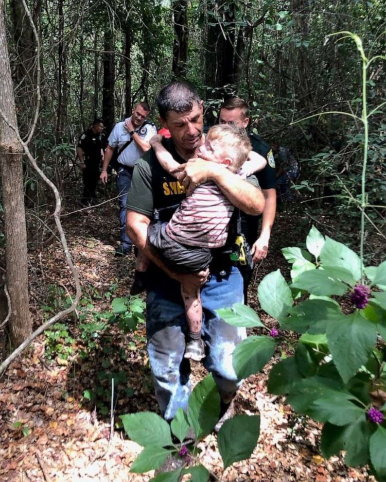 PHOTO: Boy being carried out of forest by his rescuers.