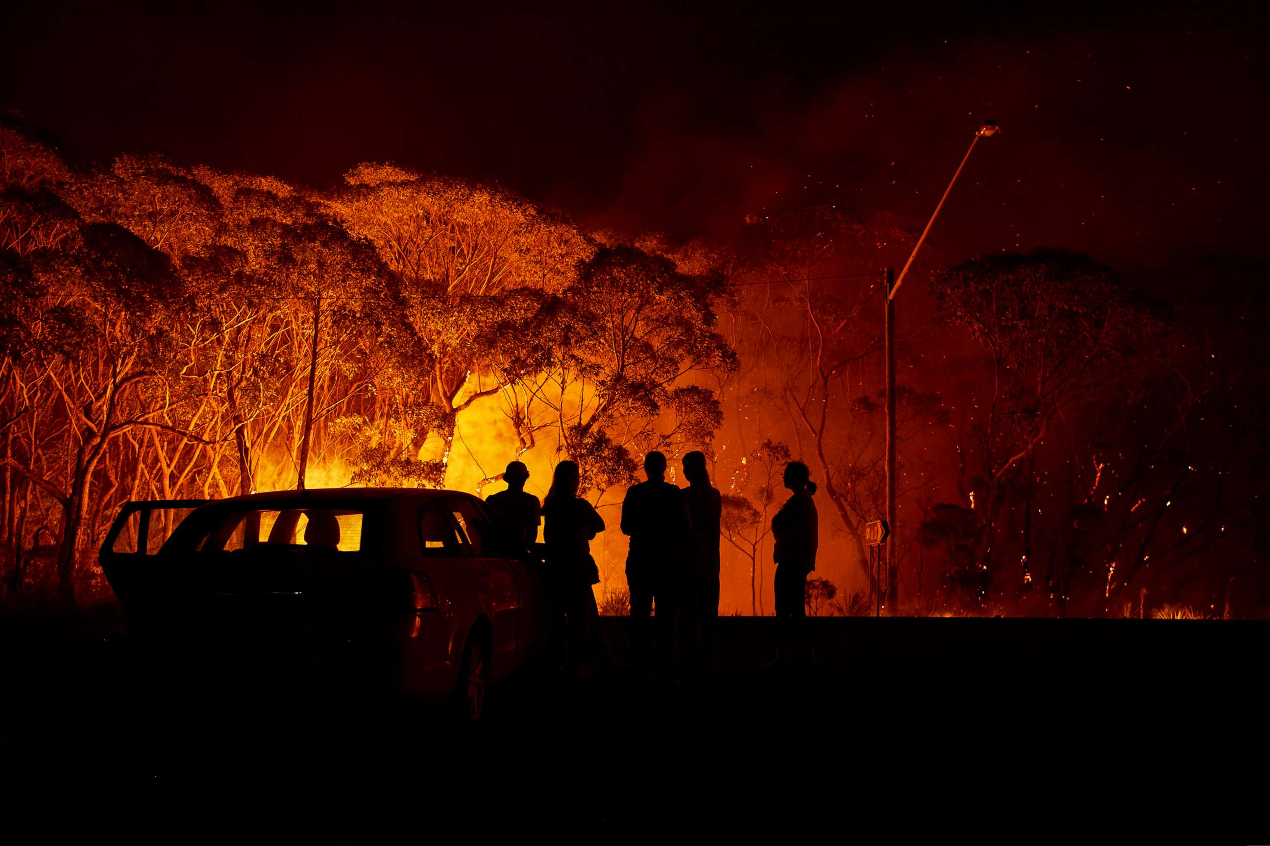 PHOTO: Residents look on as flames burn through bush on Jan. 4, 2020 in Lake Tabourie, Australia.