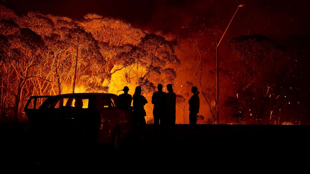 PHOTO: Residents look on as flames burn through bush on Jan. 4, 2020 in Lake Tabourie, Australia.