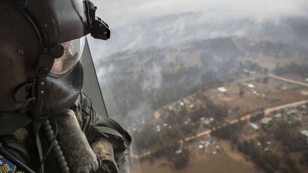 PHOTO: ELeading seaman aircrew Brendan Menz looks out of a helicopter over Southern New South Wales, Australia, Jan. 6 2020, as scattered showers fall in areas where bush  fire burn.