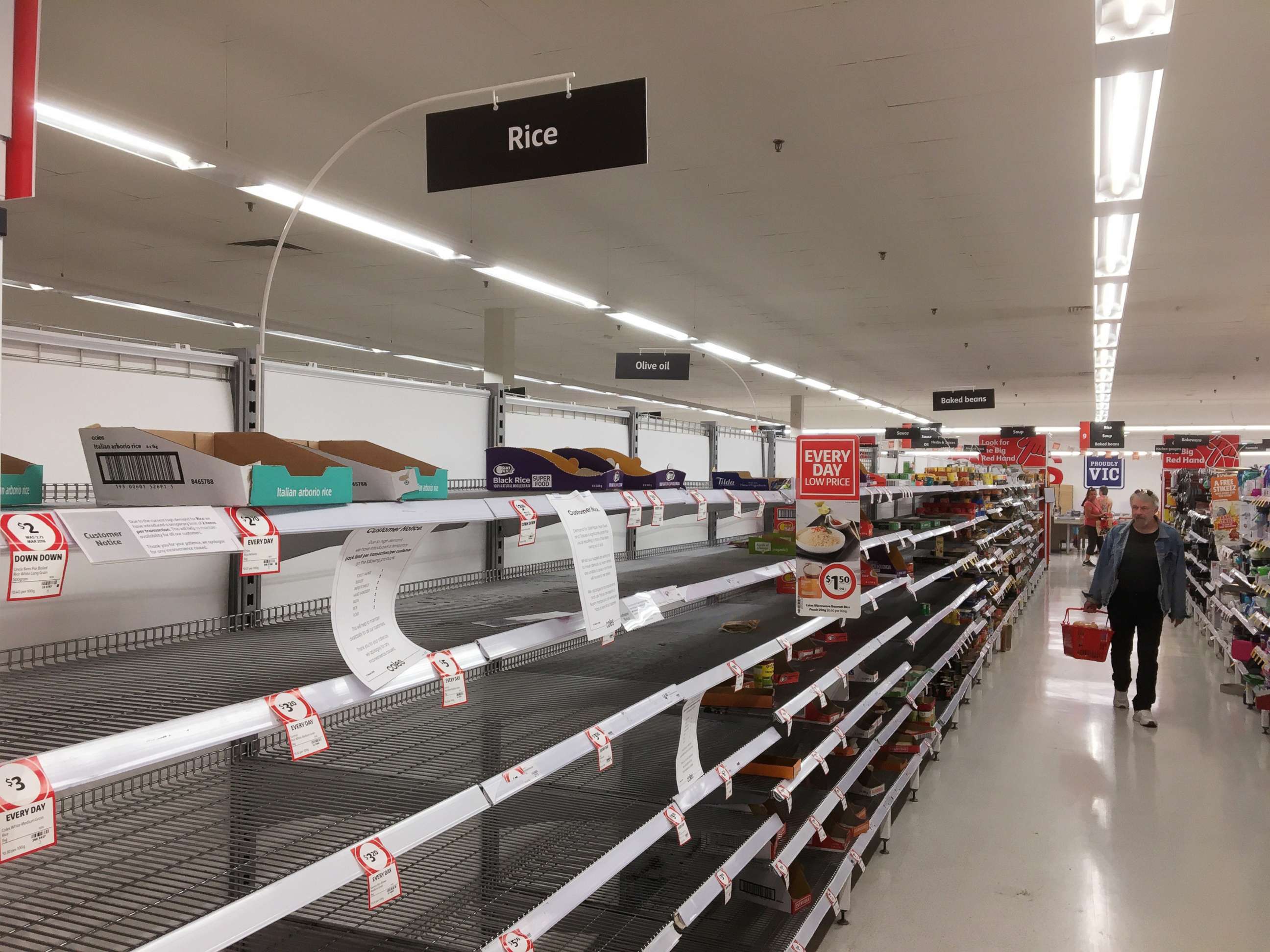 PHOTO: Shoppers walk down the aisles with empty shelves in a supermarket in Ivanhoe, Melbourne, Australia, March 16, 2020.