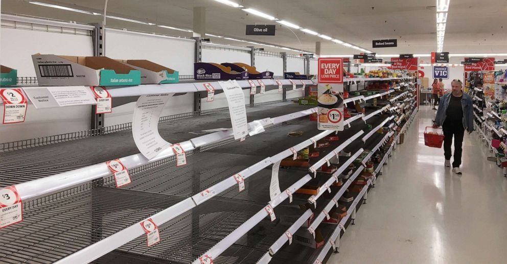 PHOTO: Shoppers walk down the aisles with empty shelves in a supermarket in Ivanhoe, Melbourne, Australia, March 16, 2020.