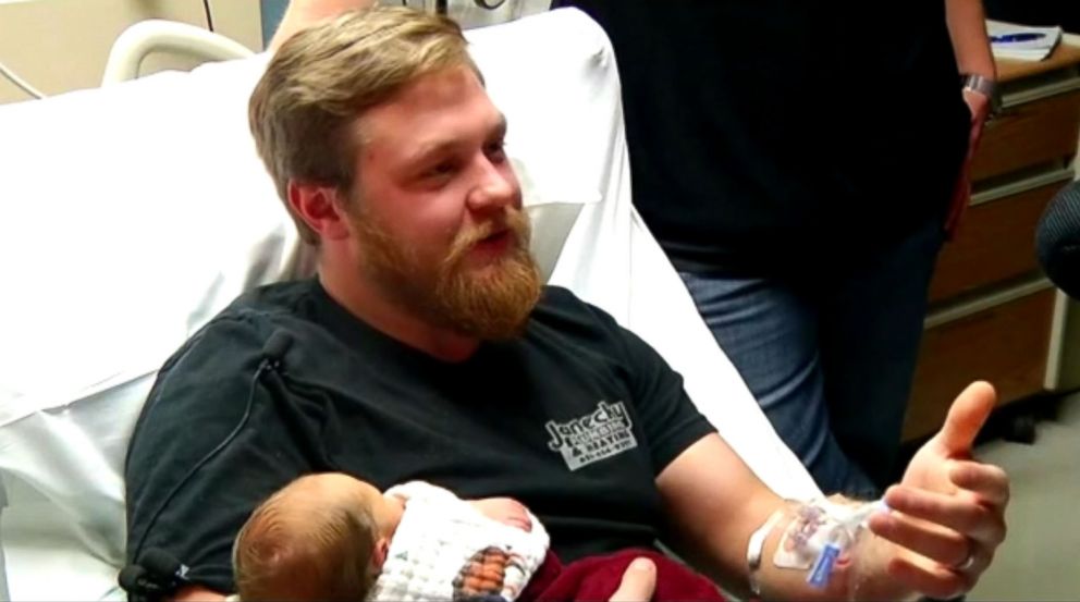 In this Tuesday, Oct. 23, 2018, photo Andrew Goette and his wife, Ashley,  look at their baby, Lennon, at United Hospital in Saint Paul, Minn. Andrew  awoke from a medically-induced coma just