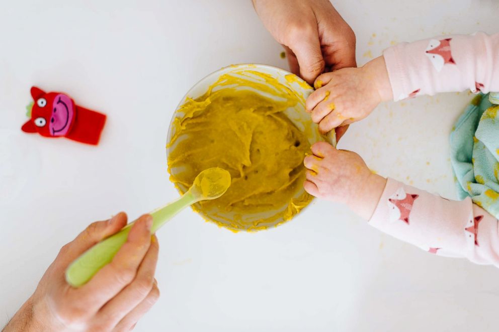 PHOTO: Hand spooning baby food.