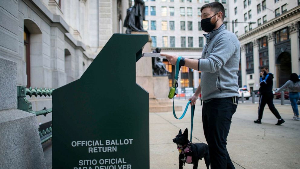 PHOTO: A voter casts his early voting ballot at drop box outside of City Hall on October 17, 2020, in Philadelphia.
