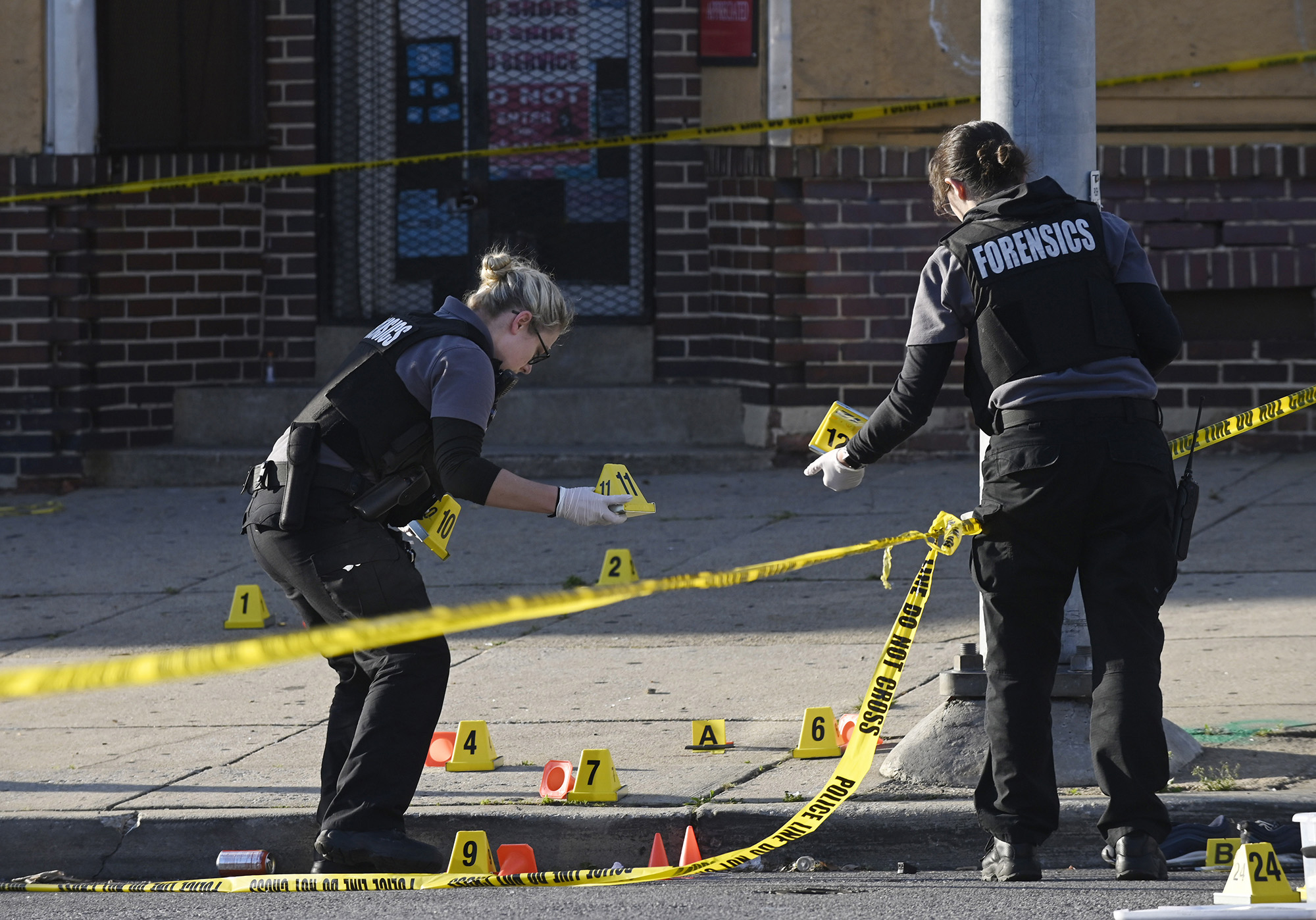 PHOTO: In this April 28, 2019, file photo, police forensics officers place evidence markers next to bullet casings while investigating the scene of a mass shooting at Edmondson and Whitmore Avenues in Baltimore.