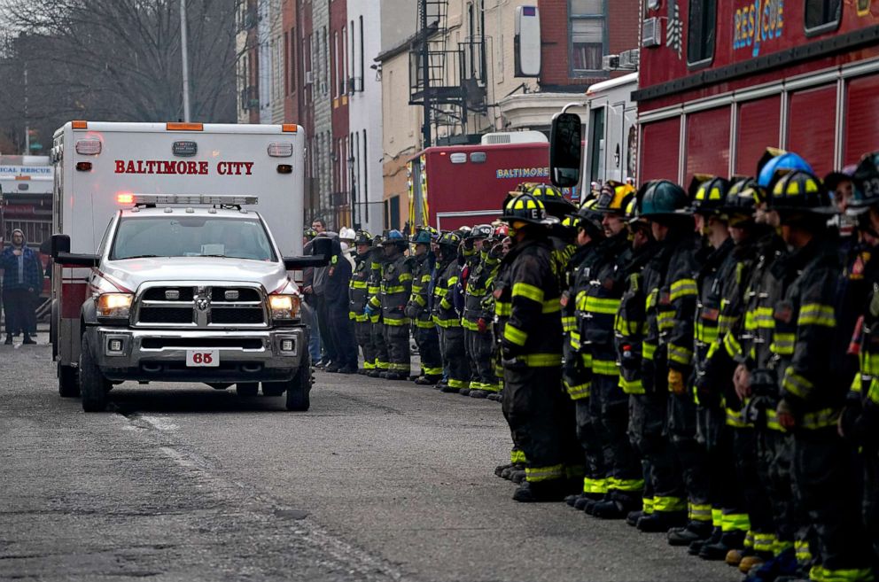 PHOTO: Firefighters salute as an ambulance carries a deceased colleague after a building collapsed while they were battling a two-alarm fire at a vacant row home, Jan. 24, 2022, in Baltimore. Three firefighters died. 
