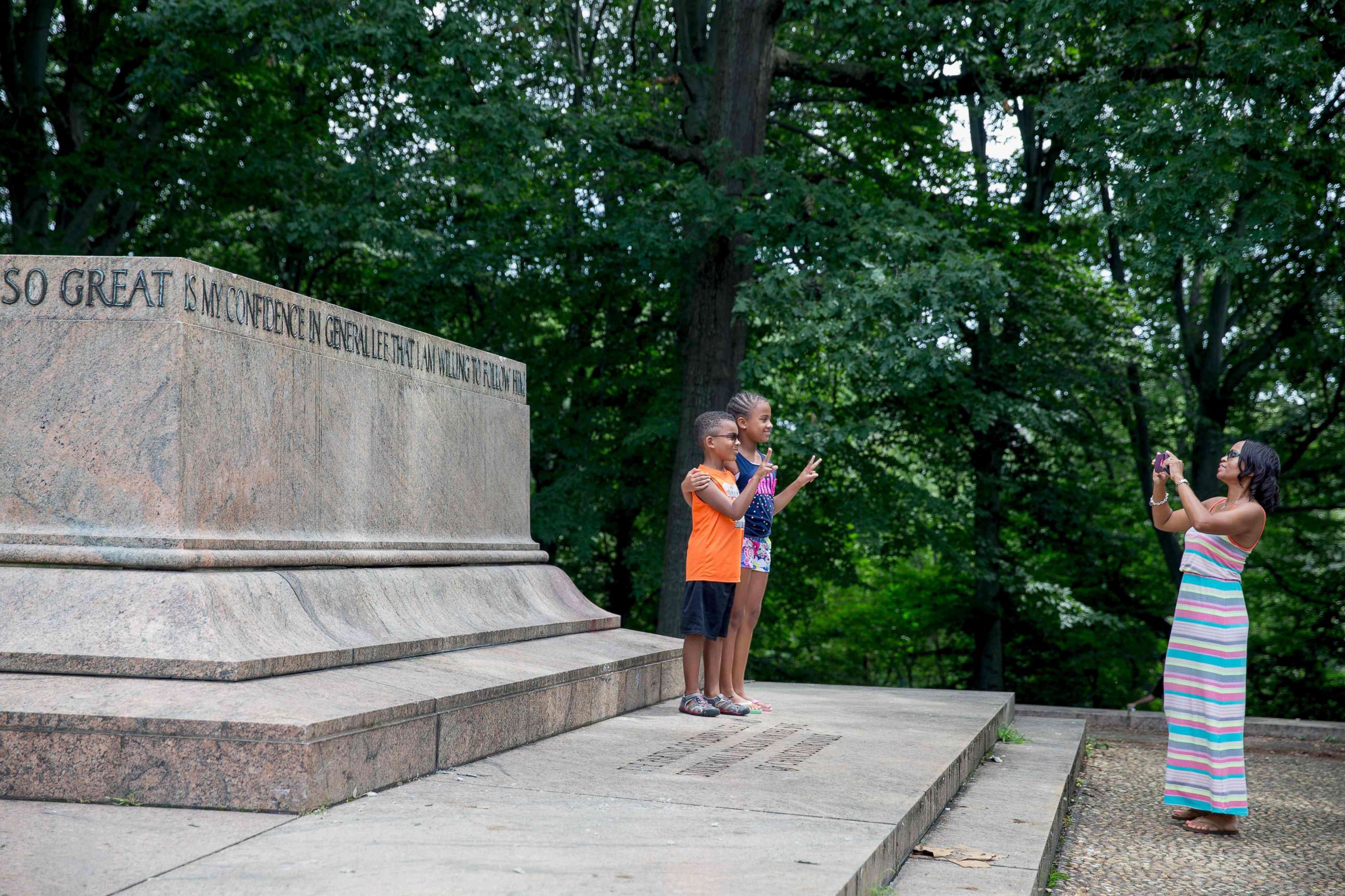 PHOTO: A family takes photos at the Robert E. Lee and Thomas J. "Stonewall" Jackson monument base in Wyman Park Dell in Baltimore after it was removed by the city on Aug. 16, 2017.
