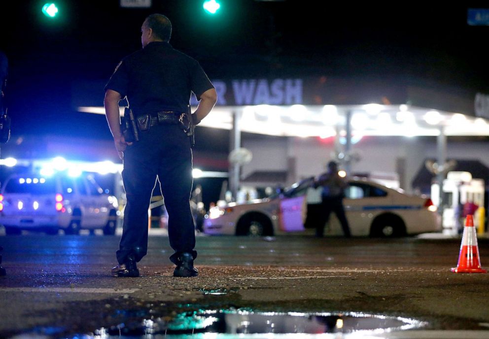 PHOTO: Police officers stand near the scene of where several police officers were killed in an ambush on July 17, 2016, in Baton Rouge, La.