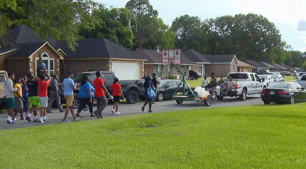 PHOTO: Residents walk with police and sheriff's office personnel in East Baton Rouge Parish, La., June 28, 2021, where music and basketball help build relationships.