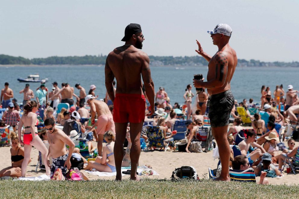 PHOTO: Two men talk as crowds gather on L Street Beach, June 5, 2021, in Boston.
