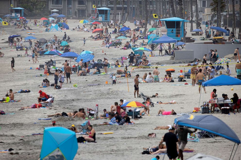 FILE PHOTO: Few people wear masks as they gather at the beach in Oceanside, California, on June 22, 2020, during the coronavirus pandemic.
