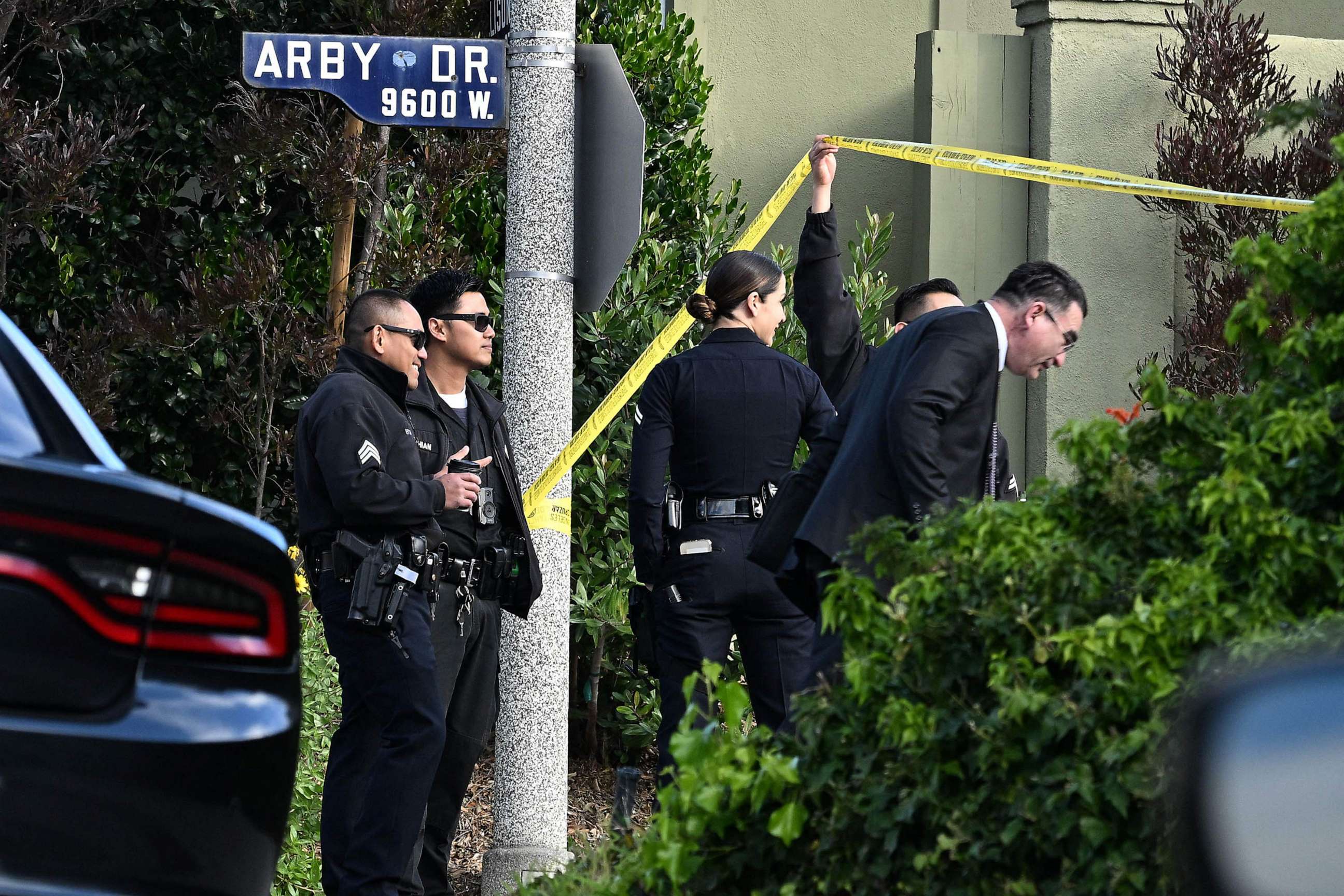 PHOTO: Police officers lift police tape for an investigator after an early morning shooting that left three people dead and four wounded, Jan. 28, 2023, in the Beverly Crest neighborhood of Los Angeles, just north of Beverly Hills.