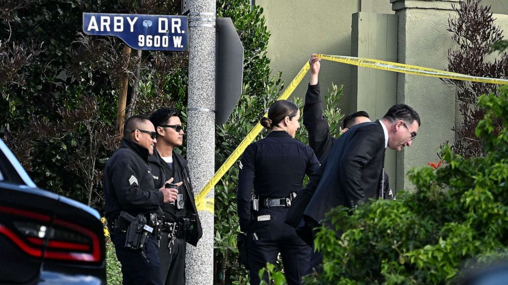PHOTO: Police officers lift police tape for an investigator after an early morning shooting that left three people dead and four wounded, Jan. 28, 2023, in the Beverly Crest neighborhood of Los Angeles, just north of Beverly Hills.