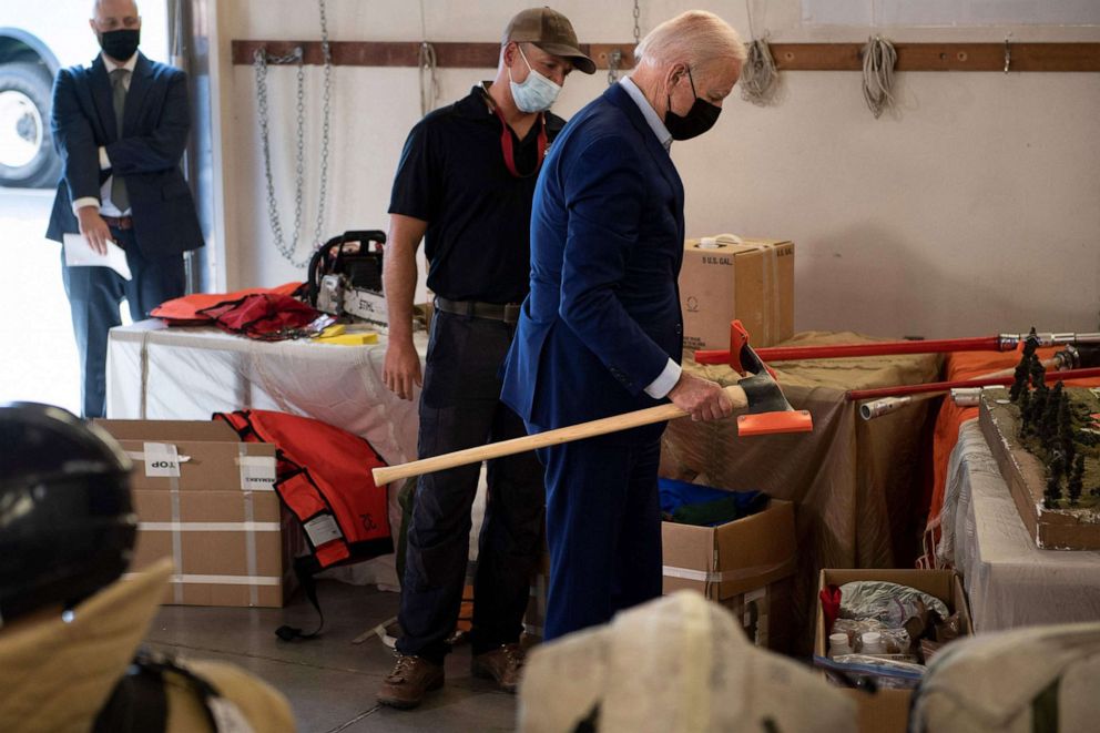 PHOTO: President Joe Biden picks up a fire fighting tool during a tour at the National Interagency Fire Center at Boise Airport, Sept. 13, 2021, in Boise, Idaho.