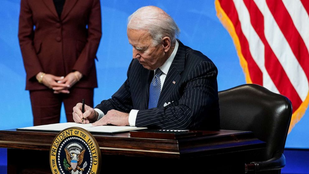 PHOTO: President Joe Biden signs an executive order after speaking about his administration's plans to strengthen American manufacturing as Vice President Kamala Harris listens at the White House in Washington, D.C., Jan. 25, 2021.