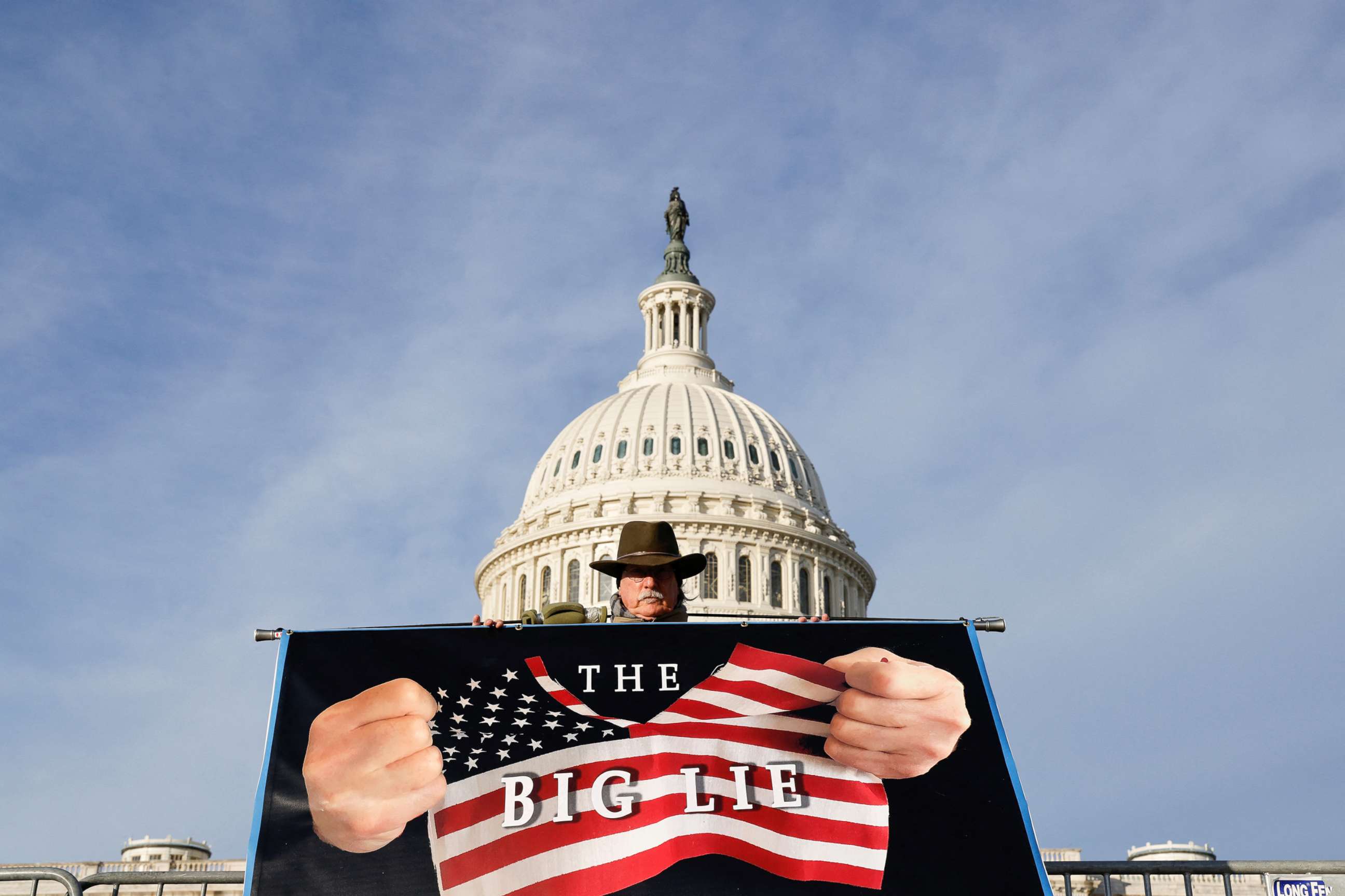 PHOTO: Artist Stephen Parlato, who is demonstrating against the January 6th attackers, holds a banner in front of the U.S. Capitol on the first anniversary of the attack, in Washington, D.C., Jan. 6, 2022.