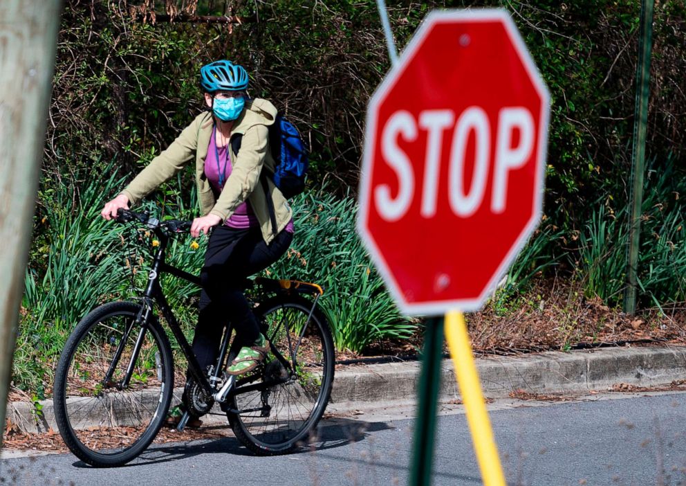 PHOTO: A woman wearing a mask, as a precautionary measure against the novel coronavirus, passes a stop sign in Mount Rainier, Maryland, near Washington, D.C., on March 30, 2020.