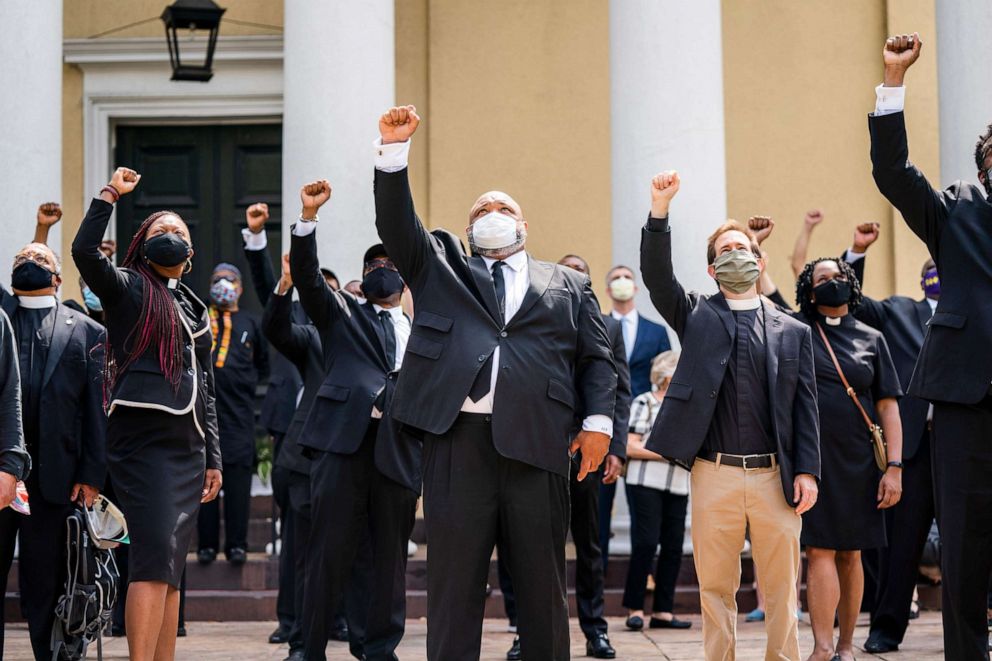PHOTO: In this June, 5, 2020, file photo, DC religious leaders raise their fists outside Saint John Church after volunteers, with permission from the city, painted 'Black Lives Matter' on 16th St. across from the White House in Washington.