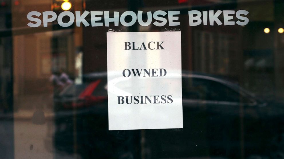 PHOTO: In this Wednesday, June 24, 2020, photograph, a sign in the window informs passersby that Spokehouse Bikes in the Upham's Corner neighborhood of Boston is a Black-owned business.