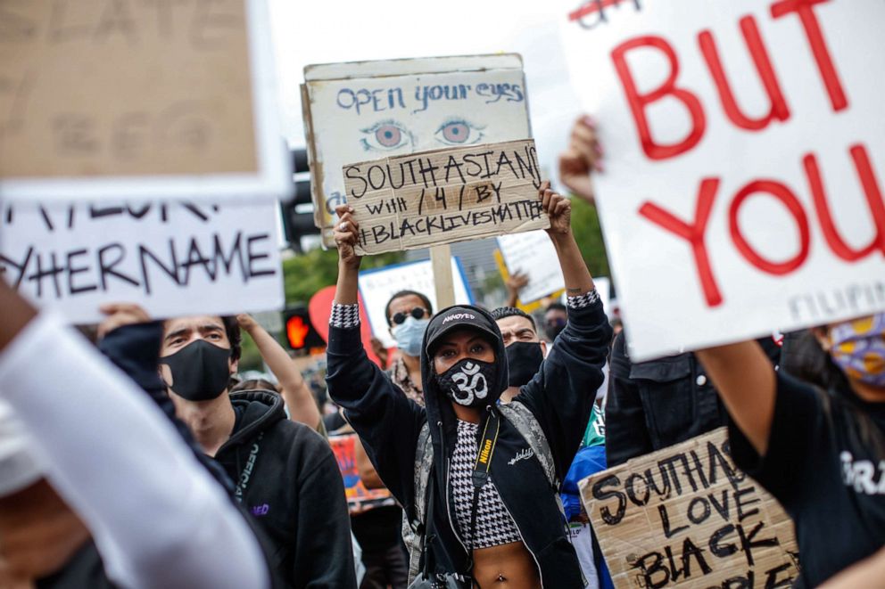 PHOTO: A woman holds a sign with the words, South Asians with / 4 / by Black Lives Matter at a protest over the death of George Floyd in downtown, Los Angeles, June 5, 2020.