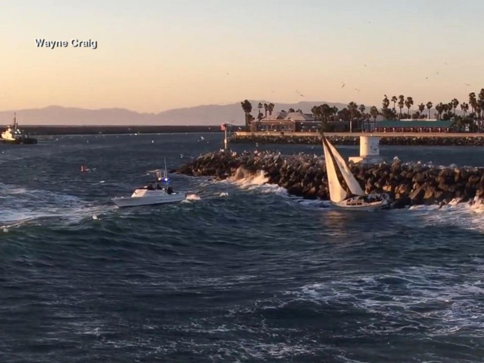 2 men, dog rescued after sailboat is swept into rocks 