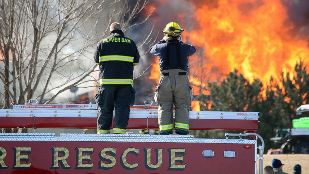 Two firefighters stand atop a truck while watching view the flames of the 109 building of Village Glen Apartments in Beaver Dam, Wisc., March 15, 2018. The fire was set to destroy hazardous chemicals in a building where an explosion killed a man on March 5, 2018. Officials concluded that burning the building with all of its contents was the only way to eliminate leftover explosive materials and hazardous chemicals. 