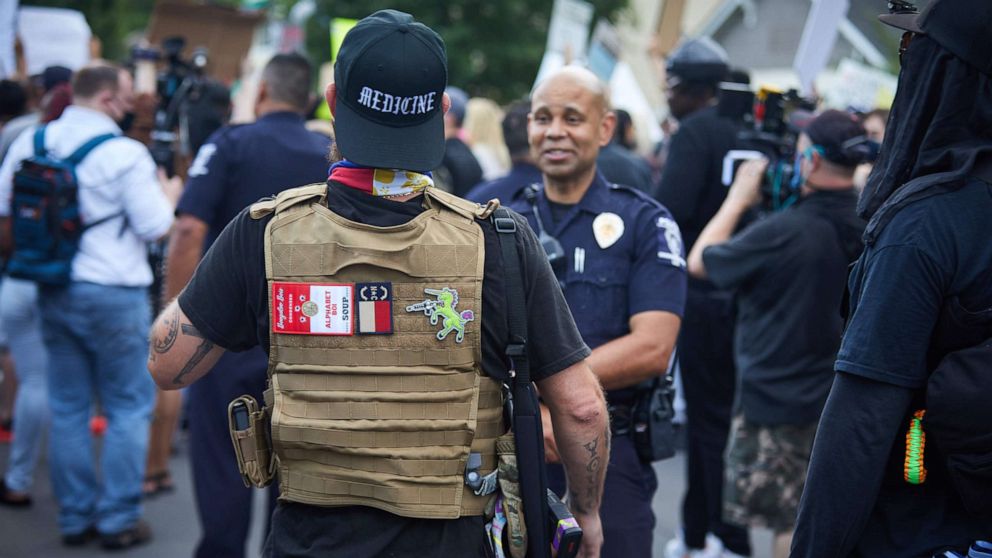 PHOTO: A member of the far-right militia, Boogaloo Bois, walks next to protestors demonstrating outside Charlotte Mecklenburg Police Department Metro Division 2 just outside of downtown Charlotte, North Carolina, on May 29, 2020. 