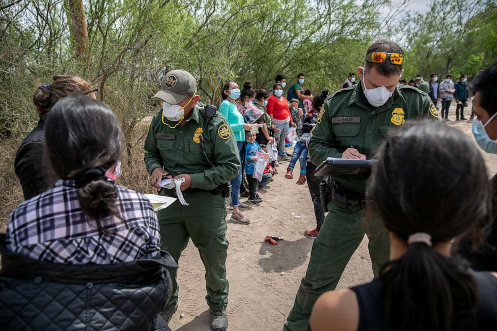 PHOTO: US Border Patrol agents question asylum seekers after their group of immigrants crossed the Rio Grande into Texas on March 25, 2021, in Hidalgo, Texas.