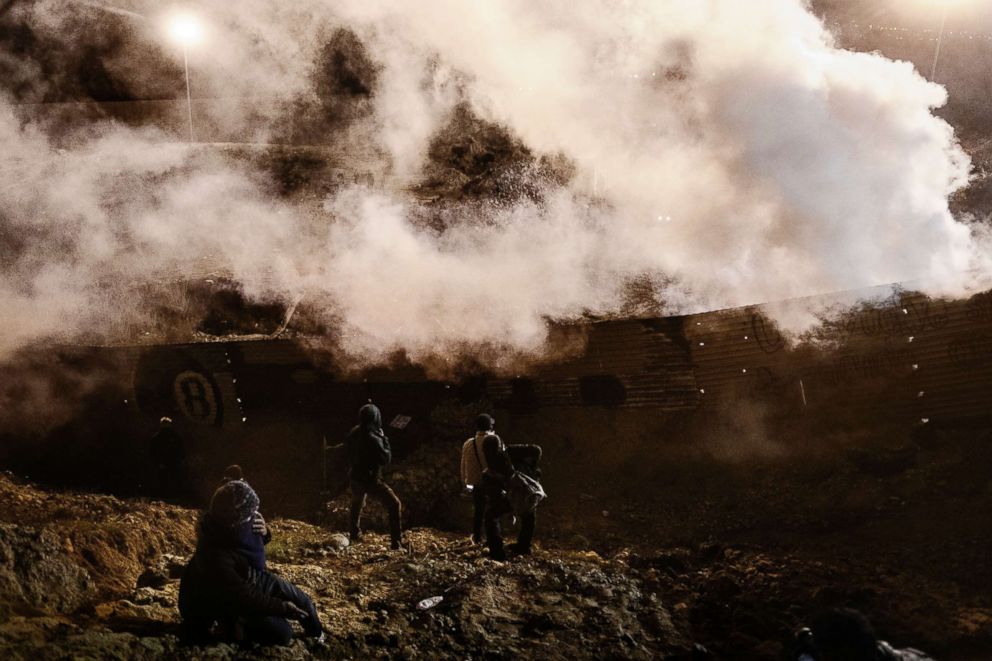 PHOTO: Migrants run as tear gas is thrown by U.S. Border Protection officers to the Mexican side of the border fence after they climbed the fence to get to San Diego, Calif., from Tijuana, Mexico, Jan. 1, 2019. 