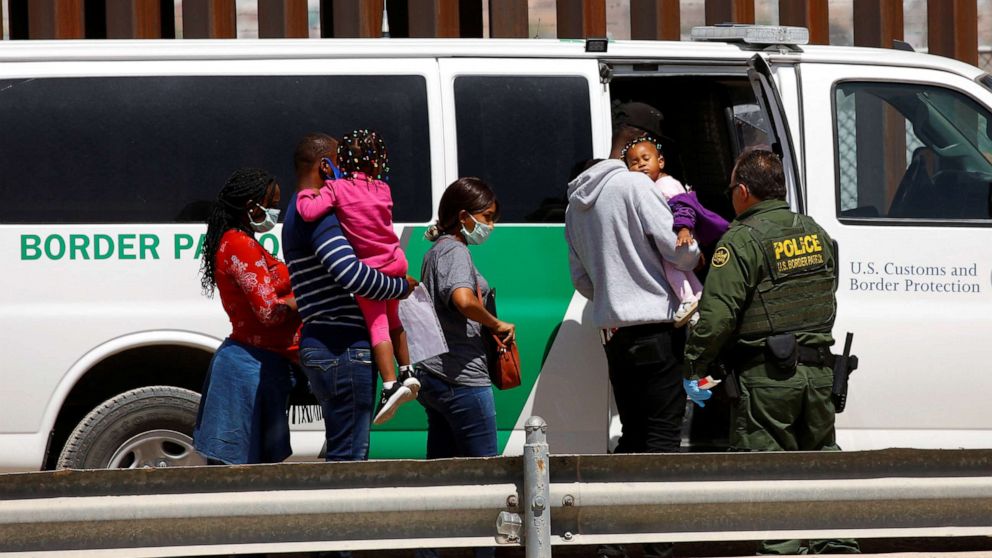 PHOTO: Asylum-seeking migrants are taken to a van by a U.S. Border Patrol agent after they crossed the Rio Bravo, in El Paso, Texas, as seen from Ciudad Juarez, Mexico, April 6, 2022.