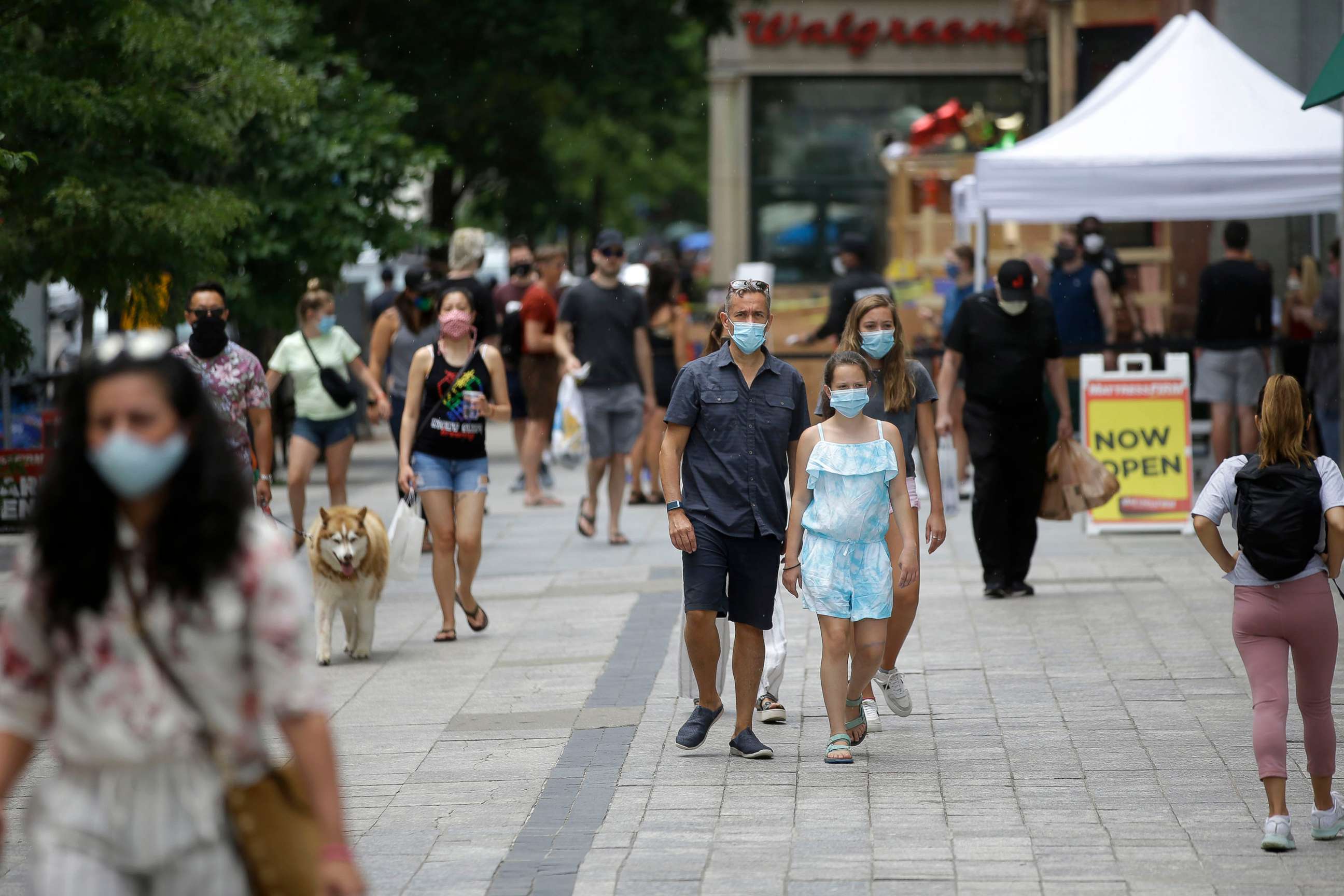 PHOTO: Pedestrians wear masks out of concern for the coronavirus, June 28, 2020, while walking along a sidewalk, in Boston.